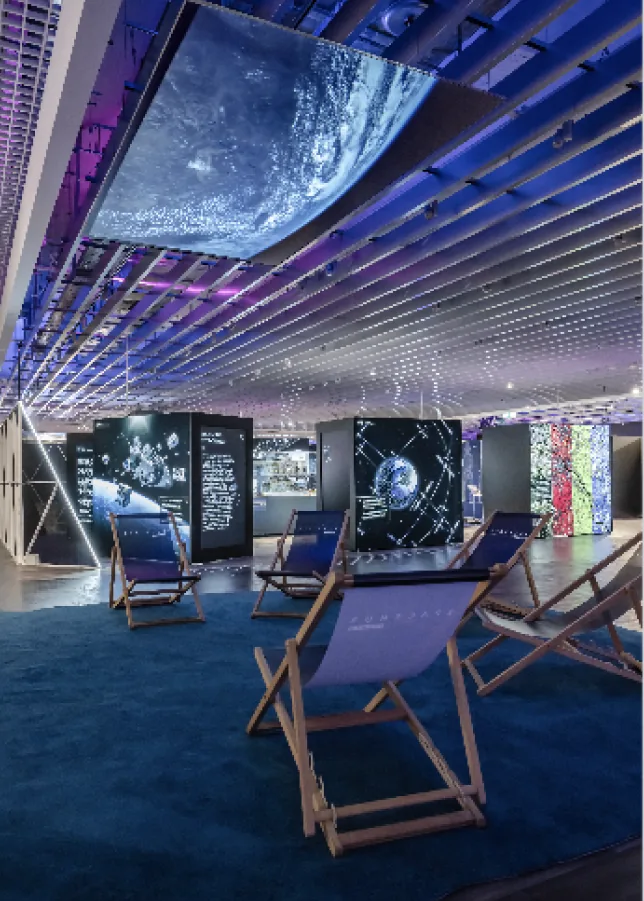 Liegestühle unter einer Weltraum-Projektion – immersive Ausstellung